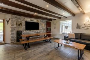 a living room with a couch and a tv on a brick wall at Grange des 2 Cols - Jacuzzi - Jardin in Campan