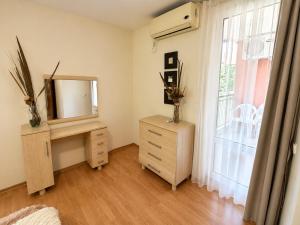a bedroom with a dresser and a mirror and a window at Two-bedroom apartment with garden view in Sunny Beach