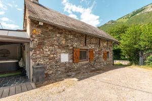 a stone house with a garage and a barn at Grange des 2 Cols - Jacuzzi - Jardin in Campan