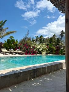 a large swimming pool with blue water and palm trees at Casa Mysa Villas in Michamvi