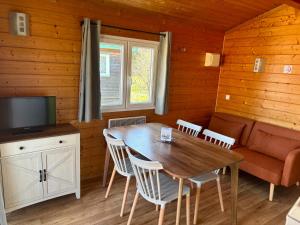 a dining room with a table and a couch at Camping Onlycamp Pierre & Sources in Volvic
