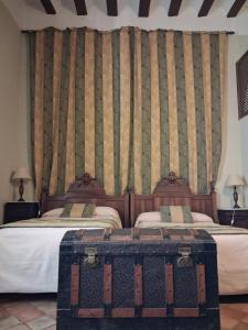 a room with two beds with a trunk on the floor at Hotel Ordóñez Sandoval in Úbeda