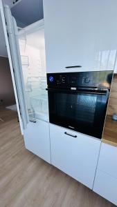 a kitchen with white cabinets and a black oven at Peaceful haven in Liepāja