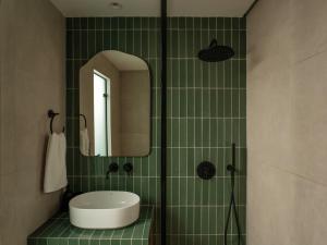 a green tiled bathroom with a sink and a mirror at Eudaimonia - Luxury Apartment in Agrinio in Agrinio