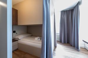 a small bedroom with a bed and blue curtains at Hotel Ochsen - Self Check-in in Uster