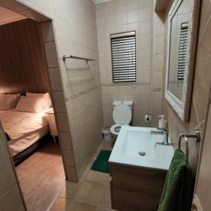 a bathroom with a sink and a toilet and a bed at L'Mida in Klerksdorp +8 photos