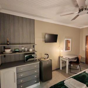 a hotel room with a bed and a desk with a microwave at L'Mida in Klerksdorp
