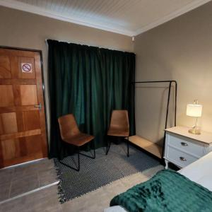 a bedroom with a green curtain and two chairs at L'Mida in Klerksdorp