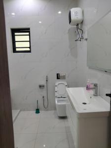 a white bathroom with a toilet and a sink at 5 bedroom apartment Magodo GRA in Sagisa +11 photos