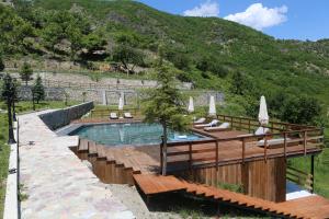 a pool with chairs and umbrellas next to a mountain at Lala Resort in Kolgecaj