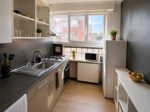 a kitchen with a sink and a white refrigerator at Le Cosy Thiers in Dunkerque