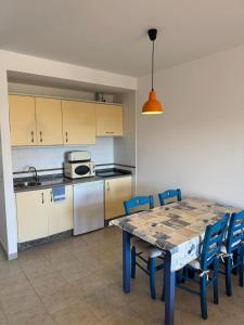 a kitchen with a table and blue chairs and a kitchen with a stove at Espalmador E10, RT259PL in Es Pujols +5 photos