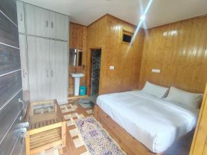 a bedroom with a white bed and wooden walls at Bhaderwah Resorts Pvt Ltd in Dranga