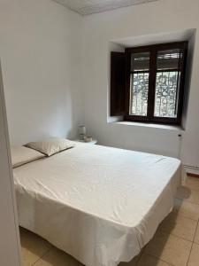 a white bed in a room with a window at La Sabonnera in Sant Llorenç de la Muga
