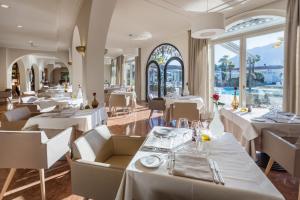 a restaurant with white tables and chairs and windows at Appartement Rosalia Delta Resort 741 in Ascona