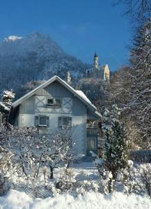 ein Haus im Schnee mit einem Berg im Hintergrund in der Unterkunft Romantic-Pension Albrecht - since 1901 in Hohenschwangau