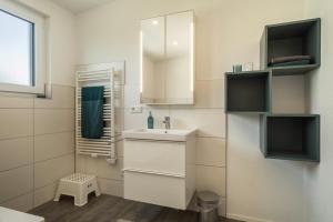 a white bathroom with a sink and a mirror at Ferienwohnung Marla in Eriskirch +19 photos