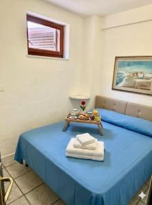 a room with a blue bed with a tray with towels at Le Case dei Ginepri in Marina di Sorso