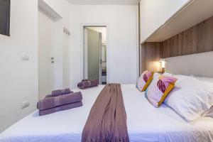 a bedroom with a large white bed with purple pillows at NURAS - DomoDé in Alghero