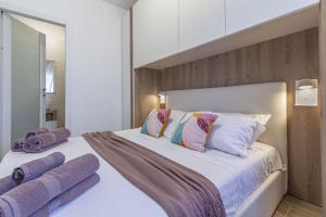 a bedroom with a large white bed with purple pillows at NURAS - DomoDé in Alghero
