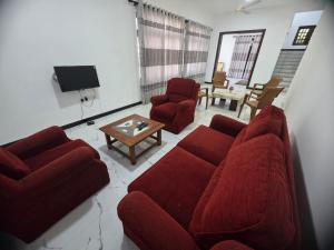 a living room with a red couch and two chairs at Villa at 37 in Badulla