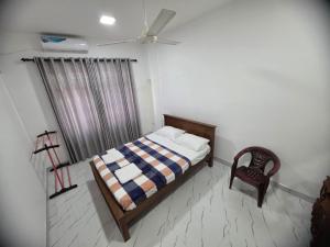 a bedroom with a bed and a chair and a window at Villa at 37 in Badulla