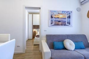 a living room with a gray couch and blue pillows at NURAS - DomoDé in Alghero
