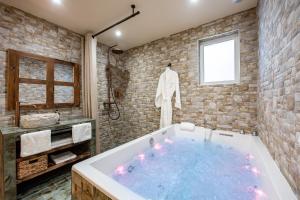 a large tub in a bathroom with a stone wall at Le Jardin de Freya - Balnéo - Centre historique in Auch +14 photos
