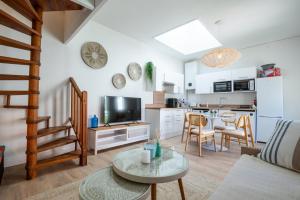 a living room with a couch and a table and a kitchen at La Cabane chic des Embruns in Cabourg