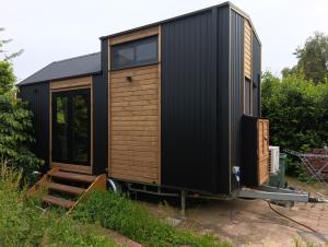 a black tiny house sitting on a trailer at Accommodatie Spiegelwaal Nijmegen Lent in Nijmegen