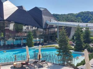 a swimming pool with umbrellas in front of a building at Terme Olimia - Apartment Lipa 112 in Podčetrtek