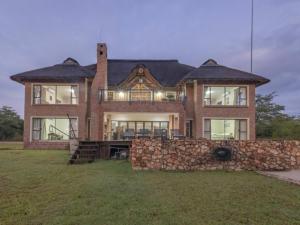 a large brick house with a stone wall at Sweet Zebula in Mabula
