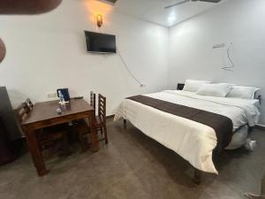 a bedroom with a bed and a desk and a television at Waves - for Family & Married Couples only in Mahabalipuram