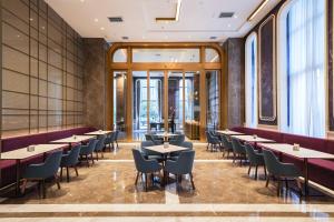 a restaurant with tables and chairs and windows at Mercure Xi'an Qujiang in Xi'an