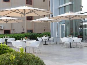 a group of tables with white chairs and umbrellas at Novotel Jazan in Jazan
