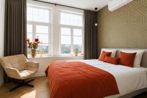 a bedroom with a bed and a chair and windows at De Zilte Melis Boutique Rooms in Meliskerke