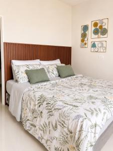 a white bedroom with a large bed with green pillows at DG Coastal Comfort near Alona Beach - Pool, Gym and Play area in Dauis +20 photos