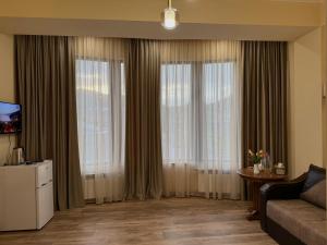 a living room with two large windows with curtains at Lalaner Hotel in Sisian +83 photos
