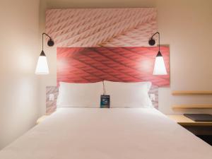 a bedroom with a large white bed with two lights at ibis Erechim in Erechim