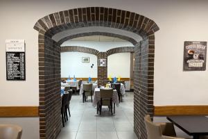 a restaurant with a brick archway with tables and chairs at Logis hôtel restaurant Auberge de la Cloche in Le Theil-sur-Huisne