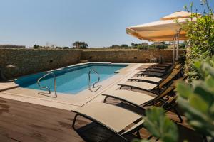 a swimming pool with lounge chairs and an umbrella at Santa Lucia Boutique Hotel in Santa Luċija