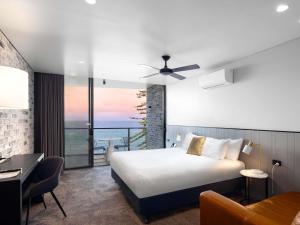 a hotel room with a bed and a view of the ocean at The Sebel Brisbane Margate Beach in Redcliffe