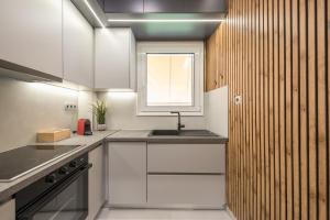 a kitchen with white cabinets and a sink and a window at West Athens Luxurius Apartment in Athens