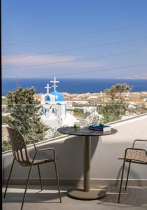 a table and chairs on a balcony with a view of a church at Anemone Luxury Suites in Fira