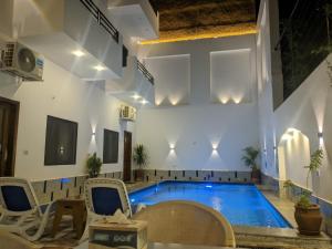 a swimming pool in a room with chairs and a table at NOOR SEEN House in Luxor