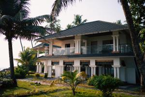 a house on the beach with palm trees at West Bay Palm Tree Beach Resort in Varkala