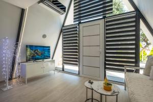 a living room with large windows and a tv at Danae's A-Frame Nest in Daratso