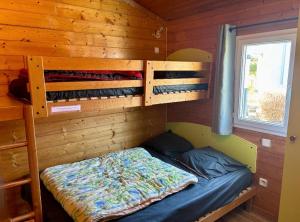 a bedroom with a bed in a wooden cabin at Camping Onlycamp Pierre & Sources in Volvic +20 photos