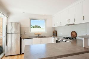 a kitchen with white cabinets and a stainless steel refrigerator at Bella Vita Beach House in Robe