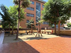 a park with a swing set in front of a building at Apartment in Castelldefels! in Castelldefels